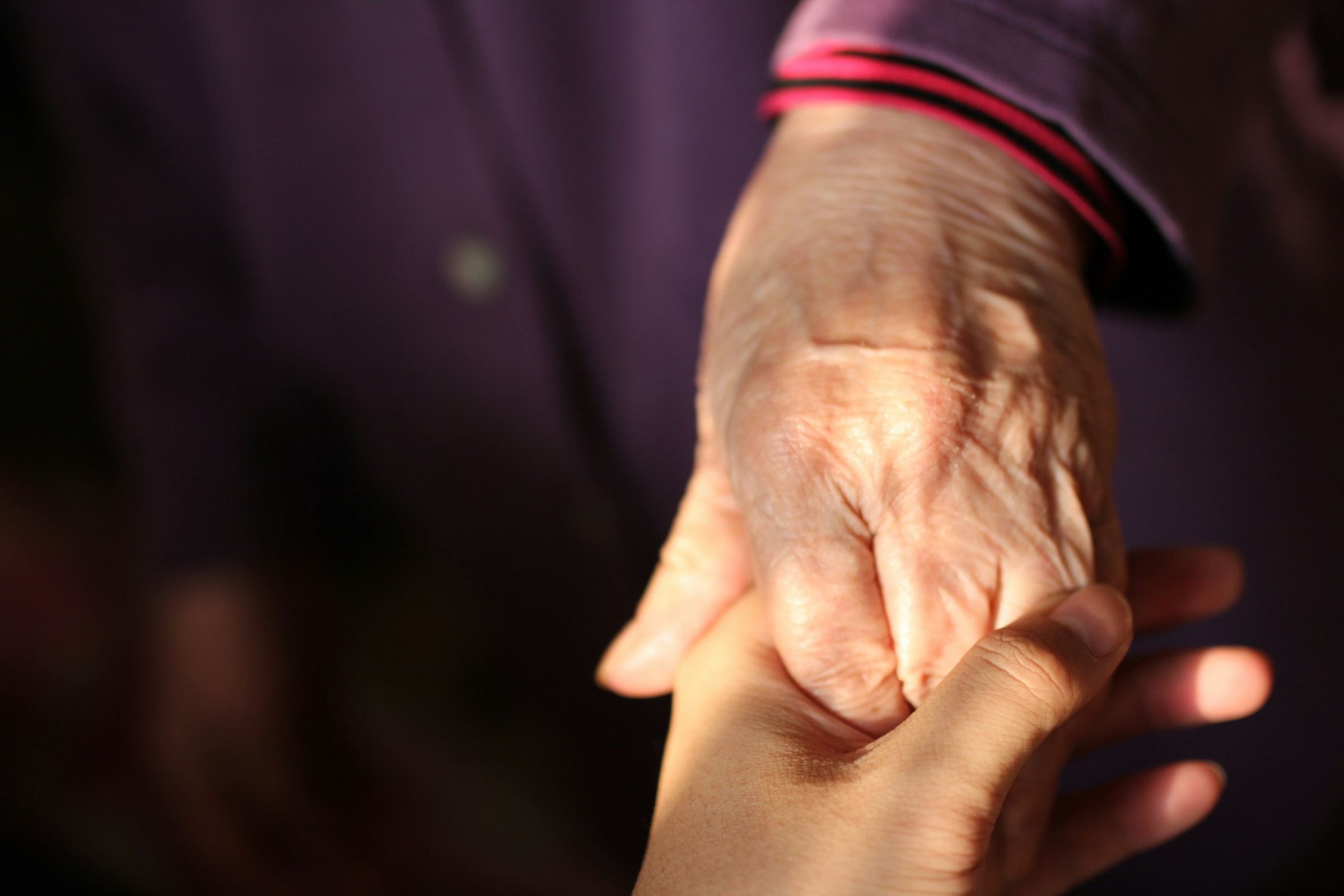 La mano di una persona anziana stretta in quella di una persona più giovane